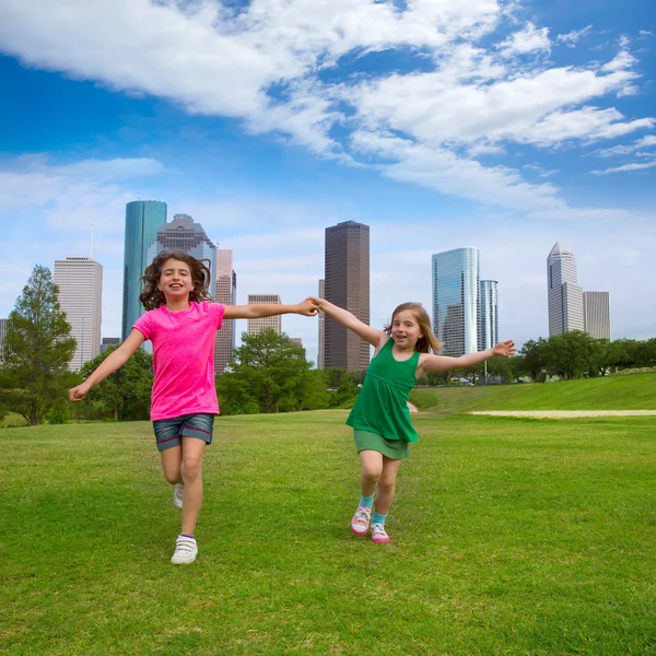 Дві подруги сестрички біжать тримаючись за руку в міському пейзажі — стокове фото