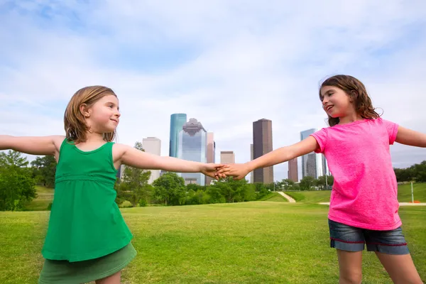 Дві подруги-сестри грають, тримаючись за руку в міському пейзажі — стокове фото