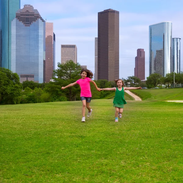 Twee zuster meisjes vrienden actief bedrijf hand in stedelijke skyline — Stockfoto
