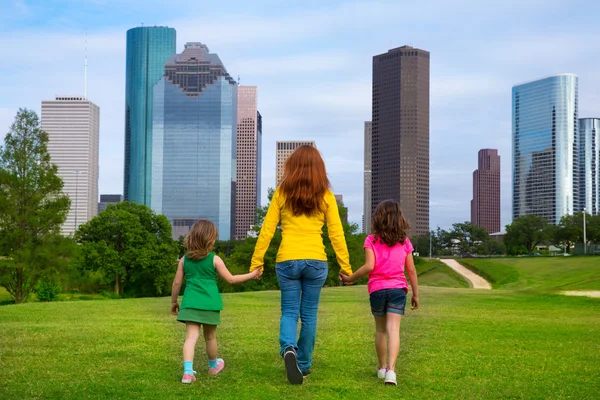 Madre e hijas caminando cogidas de la mano en el horizonte de la ciudad —  Fotos de Stock