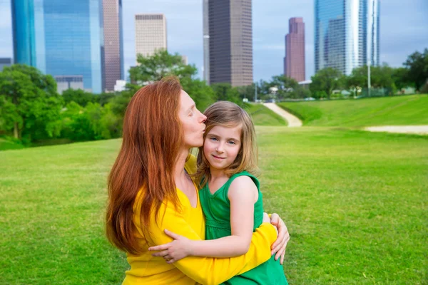 Madre e hija feliz abrazo beso en parque en horizonte de la ciudad —  Fotos de Stock