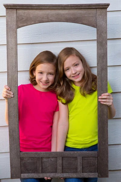 Gemelle ragazze in posa con cornice di legno invecchiato confine — Foto Stock