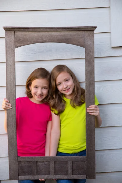 Tvillingsyster flickor poserar med äldre trä kant stomme — Stockfoto