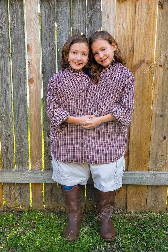 Meninas gêmeas vestidas de siamês com sua camisa do pai fotos