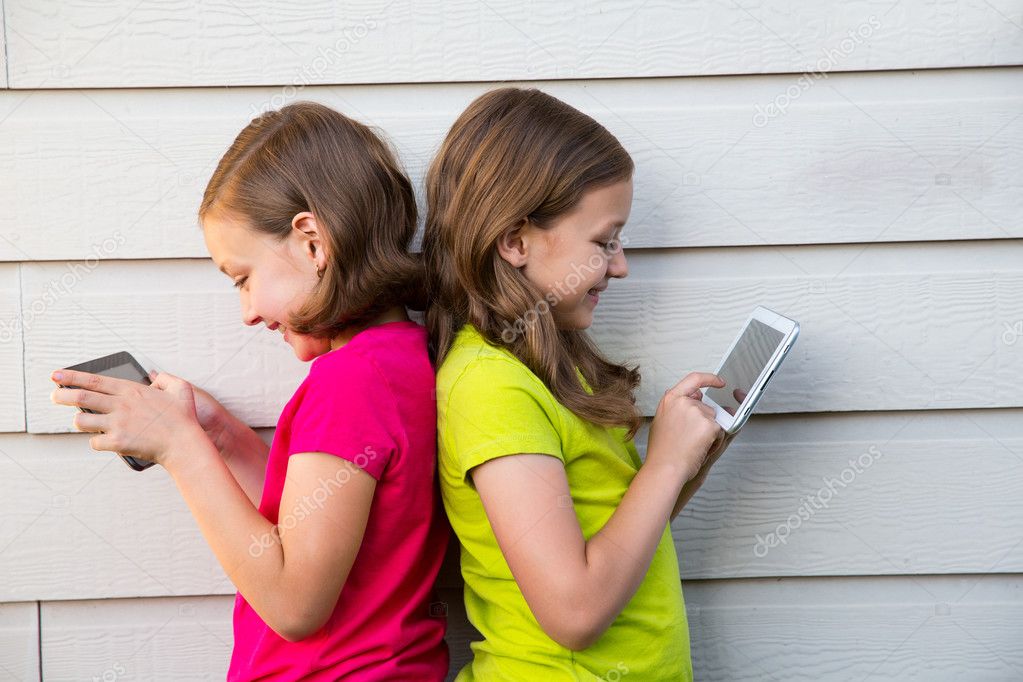 Twin sister girls playing with tablet pc happy on white wall