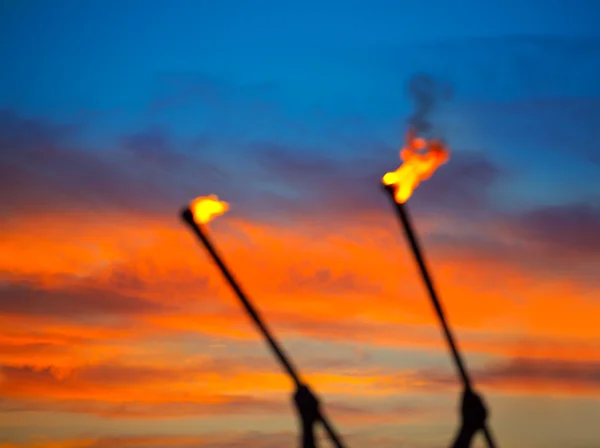 Fire torch at sunset sky with red clouds — Stock Photo, Image