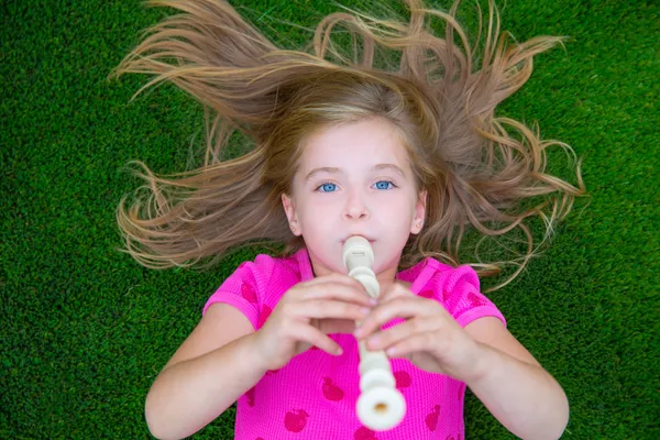 Blonda barn barn flicka spela flöjt liggande på gräs — Stockfoto