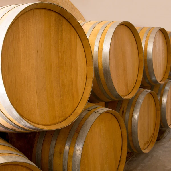 Vino barricas de roble de madera apiladas en una fila en la bodega — Foto de Stock