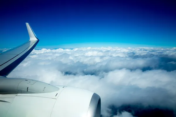 Ala di aeroplano che vola sopra le nuvole soffici nel cielo blu — Foto Stock