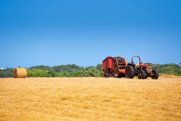 Menorca kombinují traktor pšenice s kulatých balíků — Stock fotografie