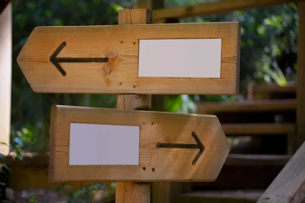 Wooden road sign with two opposite arrow directions — Stock Photo, Image