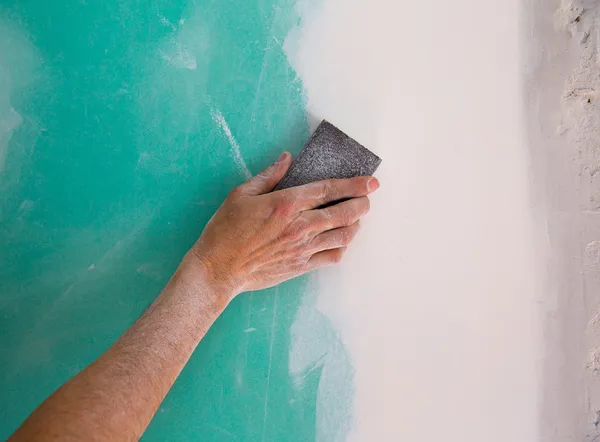 Plastering man hand sanding the plaste in drywall seam — Stock Photo, Image
