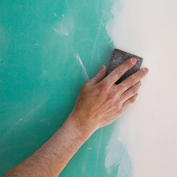 Plastering man hand sanding the plaste in drywall seam — Stock Photo, Image