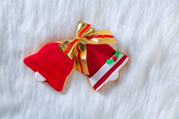 Christmas cookies red bell shape and ribbon on white fur — Stock Photo, Image