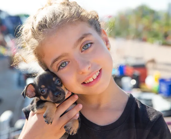 Девочка играет с щенком, улыбаясь — стоковое фото