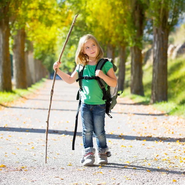 Ragazzina bionda esploratrice che cammina con lo zaino negli alberi autunnali — Foto Stock