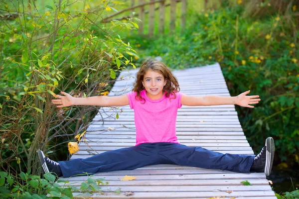 Enfant fille en automne souriant avec bretelles bras ouverts et les jambes — Photo