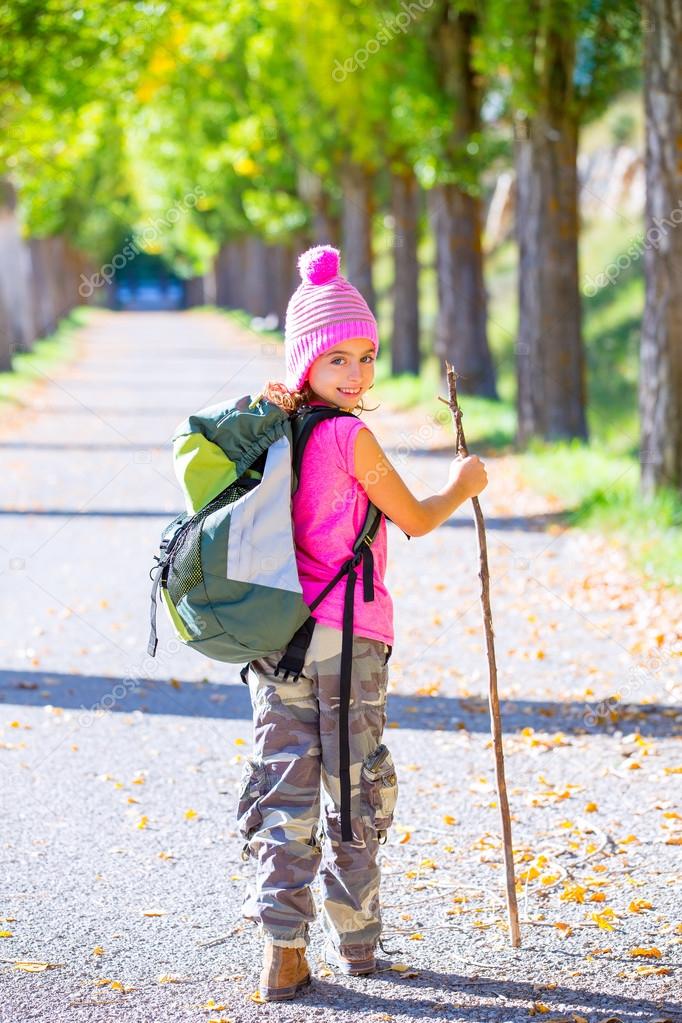 hiking kid girl with walking stick and backpack in autumn