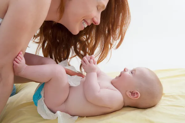 Bambino con madre diapering e giocare sorridente — Foto Stock
