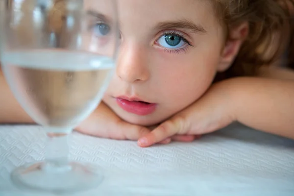 蓝色的大眼睛蹒跚学步的女孩看着相机从一杯水 — 图库照片