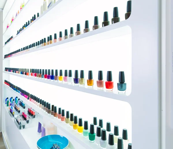 Colores de esmalte de uñas de colores en una fila en salón de uñas en blanco — Foto de Stock