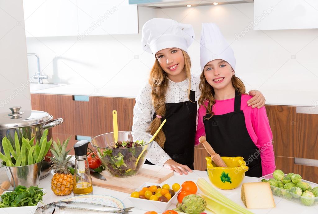 Kid girls junior chef friends hug together at cooking school