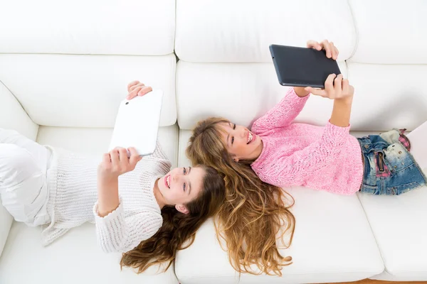 Niñas que se divierten jugando con la tableta pc sofá acostado — Foto de Stock