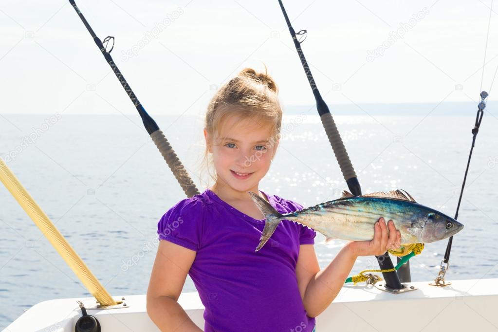 Blond girl fishing bonito Sarda tuna trolling in sea