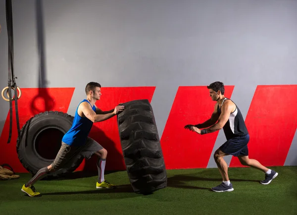 Homens lançando um pneu trator exercício de ginástica — Fotografia de Stock