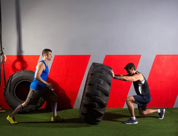 Homens lançando um pneu trator exercício de ginástica — Fotografia de Stock