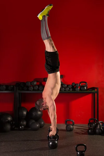 Kettlebell handstand man workout in red gym — Stock Photo, Image