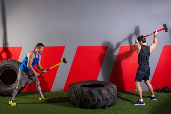 Sledgehammer Tire Golpea a los hombres entrenamiento en el gimnasio —  Fotos de Stock