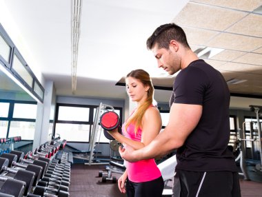 Gym personal trainer man with dumbbell woman