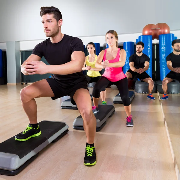 Grupo de agachamento de dança de passo cardio no ginásio de fitness — Fotografia de Stock