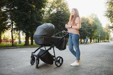 mutlu genç anne ile bebek arabası sonbahar parkta yürüyüş
