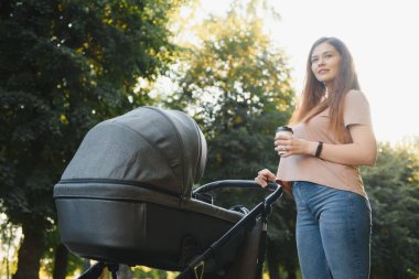 Annem bankta oturuyor. Bebek arabasında oturan bir kadın bebeğini itiyor. Aile kavramı.