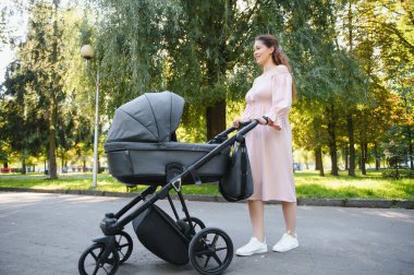 Aile, çocuk ve ebeveyn kavramı - mutlu anne ile bebek arabası Park yürüme.