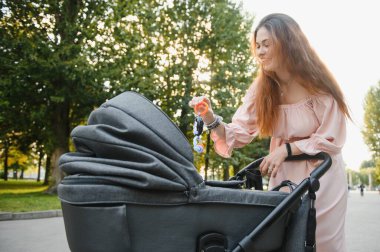 mutlu genç anne ile bebek arabası sonbahar parkta yürüyüş