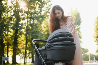 Annem caddede yürüyor. Bebek arabasında oturan bir kadın bebeğini itiyor. Aile kavramı.