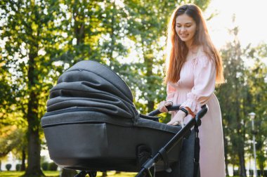Annem caddede yürüyor. Bebek arabasında oturan bir kadın bebeğini itiyor. Aile kavramı.