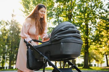 mutlu genç anne ile bebek arabası sonbahar parkta yürüyüş