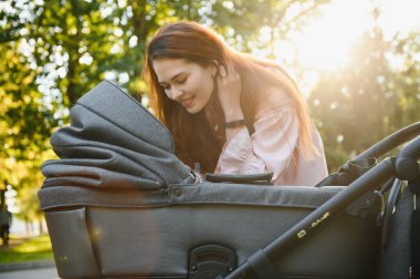 Aile, çocuk ve ebeveyn kavramı - mutlu anne ile bebek arabası Park yürüme.