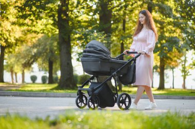 Aile, çocuk ve ebeveyn kavramı - mutlu anne ile bebek arabası Park yürüme.