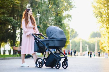 mutlu genç anne ile bebek arabası sonbahar parkta yürüyüş