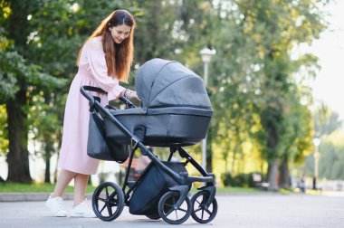 Annem caddede yürüyor. Bebek arabasında oturan bir kadın bebeğini itiyor. Aile kavramı.