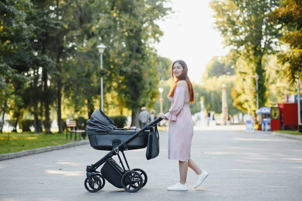 Annem caddede yürüyor. Bebek arabasında oturan bir kadın bebeğini itiyor. Aile kavramı.