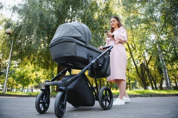 mutlu genç anne ile bebek arabası sonbahar parkta yürüyüş