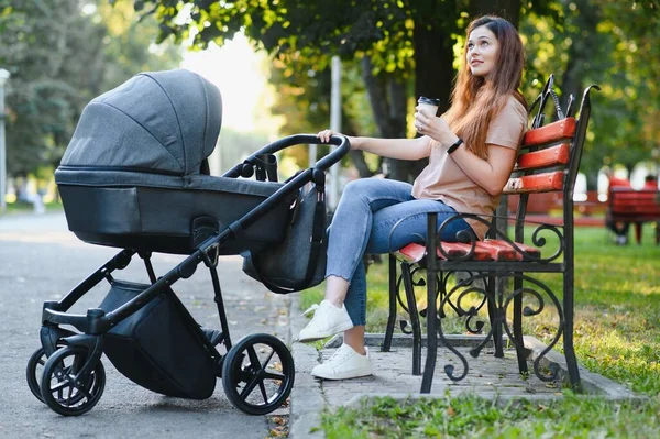 Annem bankta oturuyor. Bebek arabasında oturan bir kadın bebeğini itiyor. Aile kavramı.