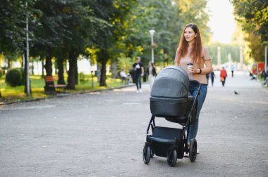 güzel ve genç kadın anne ve Bebek arabasındaki bebek parkta yürüyüş