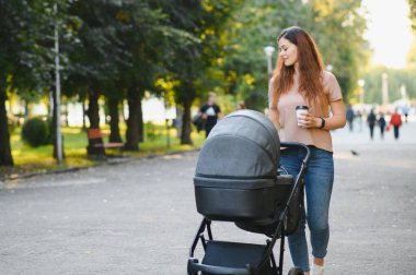Annem caddede yürüyor. Bebek arabasında oturan bir kadın bebeğini itiyor. Aile kavramı.